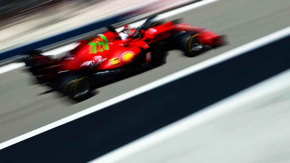 Charles Leclerc drives down the pit line in his red Ferrari.