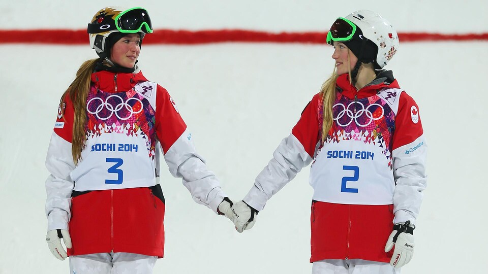 Deux skieuses se regardent en se tenant la main
