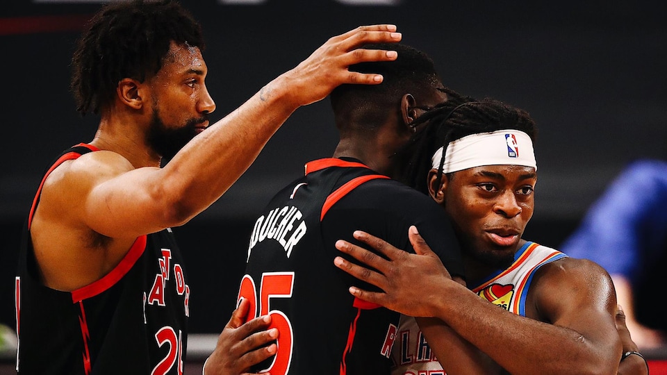 Trois joueurs de basketball se font une accolade.
