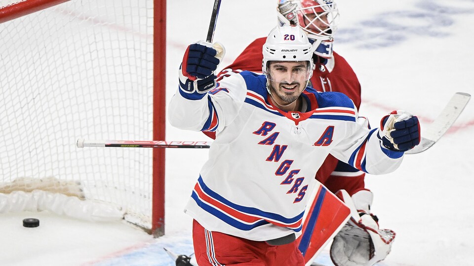 Un hockeyeur sourit après avoir marqué un but.