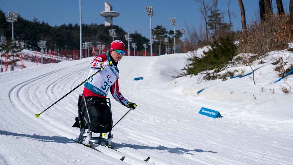 Elle est assise dans un fauteuil muni de skis de fond.