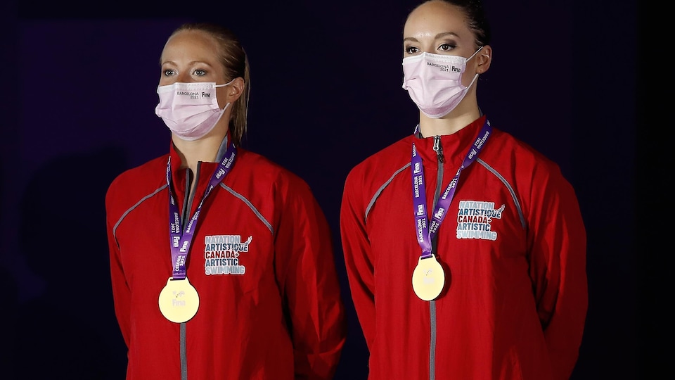 Les deux femmes, portant un couvre-visage, ont une médaille d'or autour du cou.