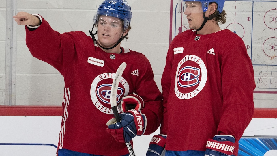 Deux joueurs en rouge discutent sur la patinoire.