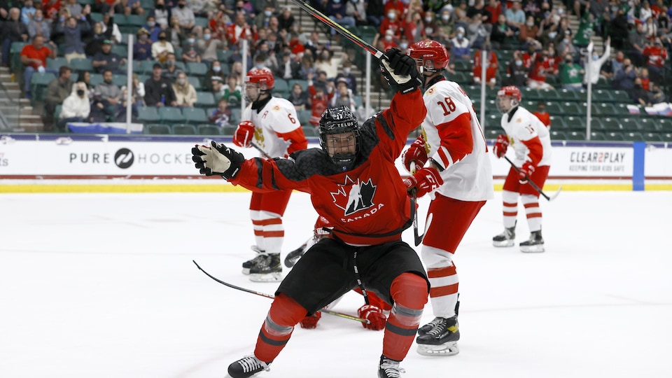 Le joueur de hockey canadien lève son bâton au ciel et célèbre son but.