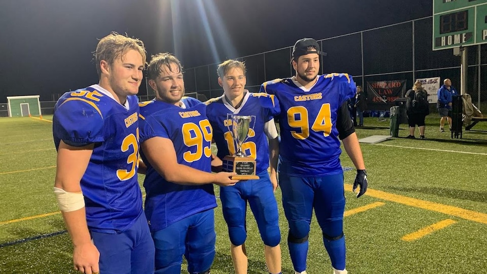 Joueurs avec équipements de football tiennent un trophée.