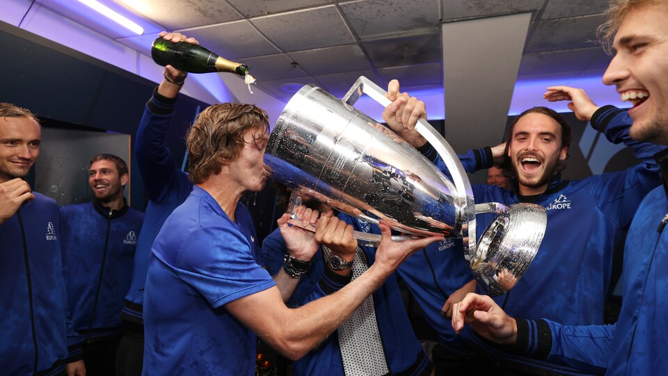 Des hommes boivent du champagne à même une immense coupe en métal.