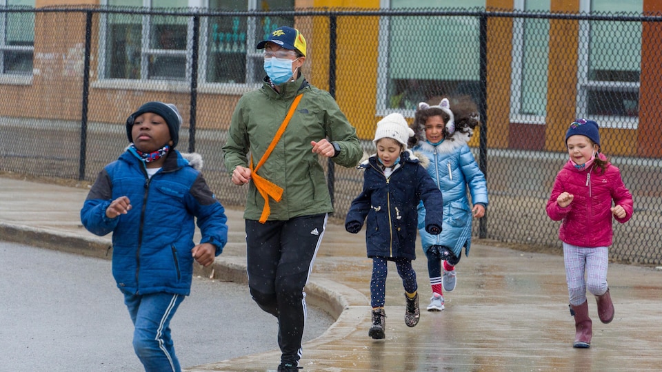Une enseignante fait de la course avec ses jeunes élèves près de son école. 