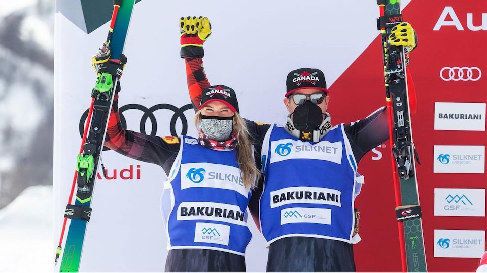 Ils lèvent leurs bras et leurs skis sur le podium.