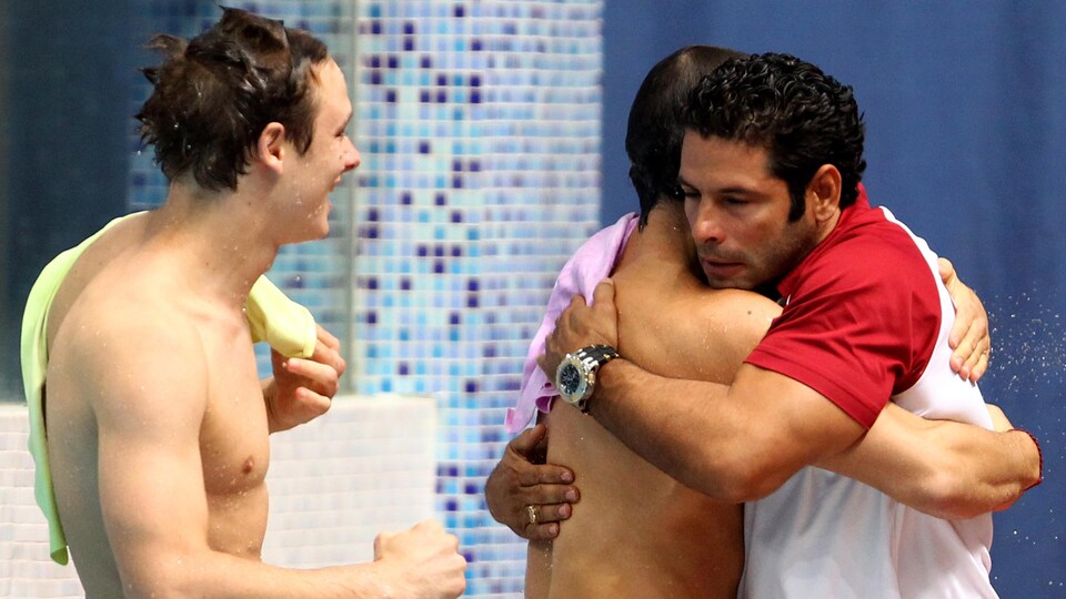 Arturo Miranda sert une accolade à Alexandre Despatie après sa victoire au 3m synchro en compagnie de Ruben Ross (à gauche) aux Jeux du Commonwealth 2010, à New Dehli.