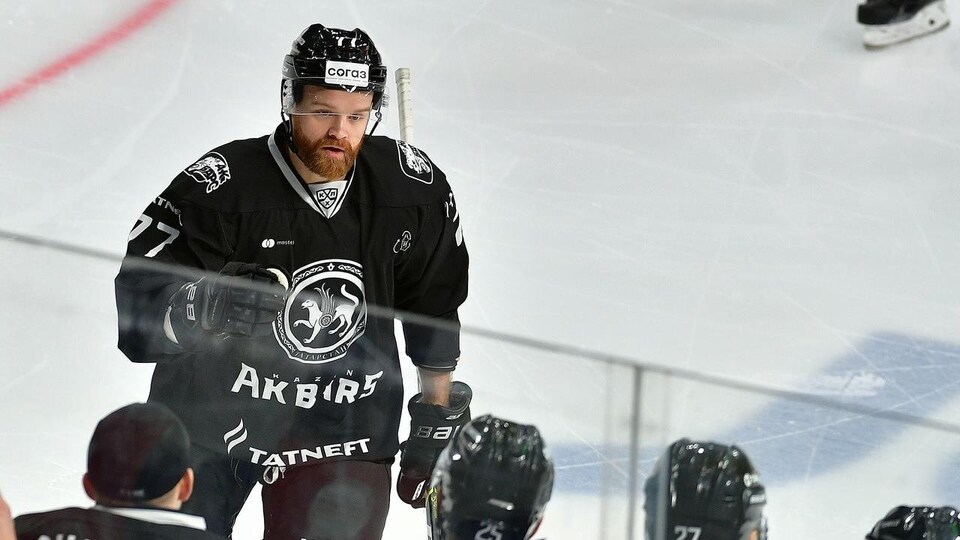 Vêtu de l'uniforme noir de son équipe, il va célébrer un but au banc des siens.