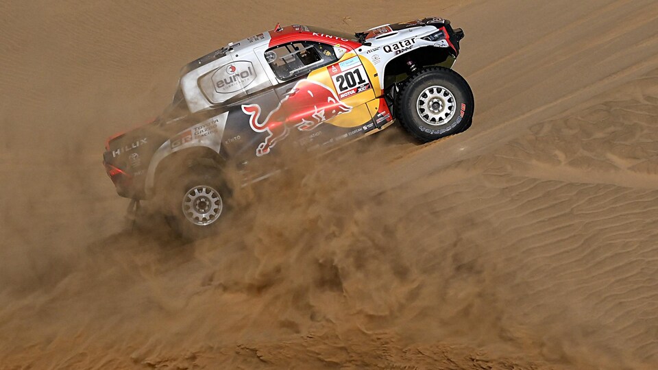 Une camionnette commanditée roule sur une dune de sable.