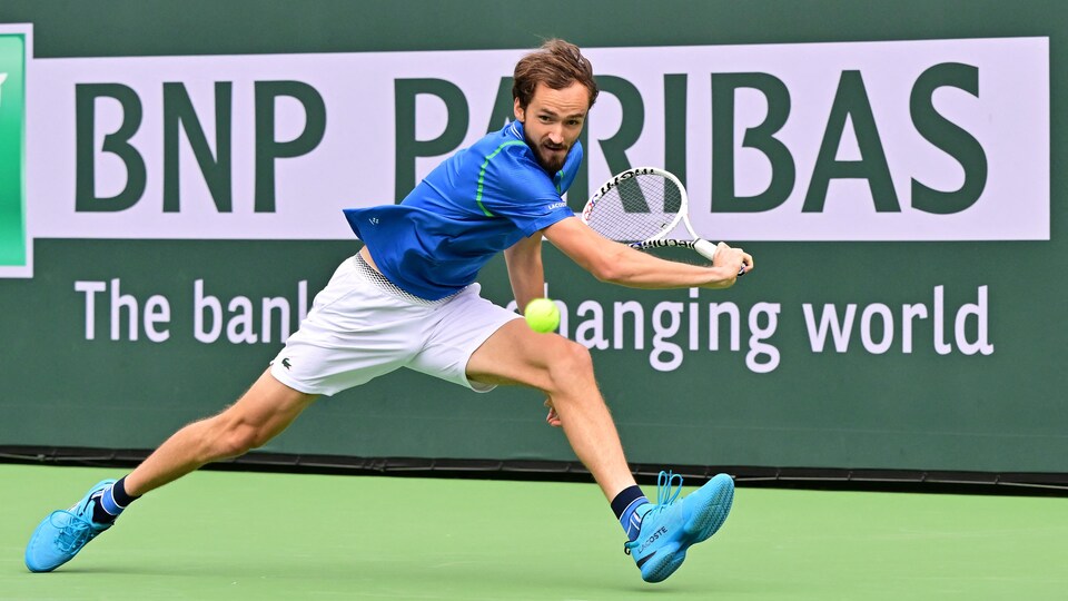 Le joueur de tennis Daniil Medvedev s'étire de tout son long pour retourner une balle avec le revers de sa raquette.