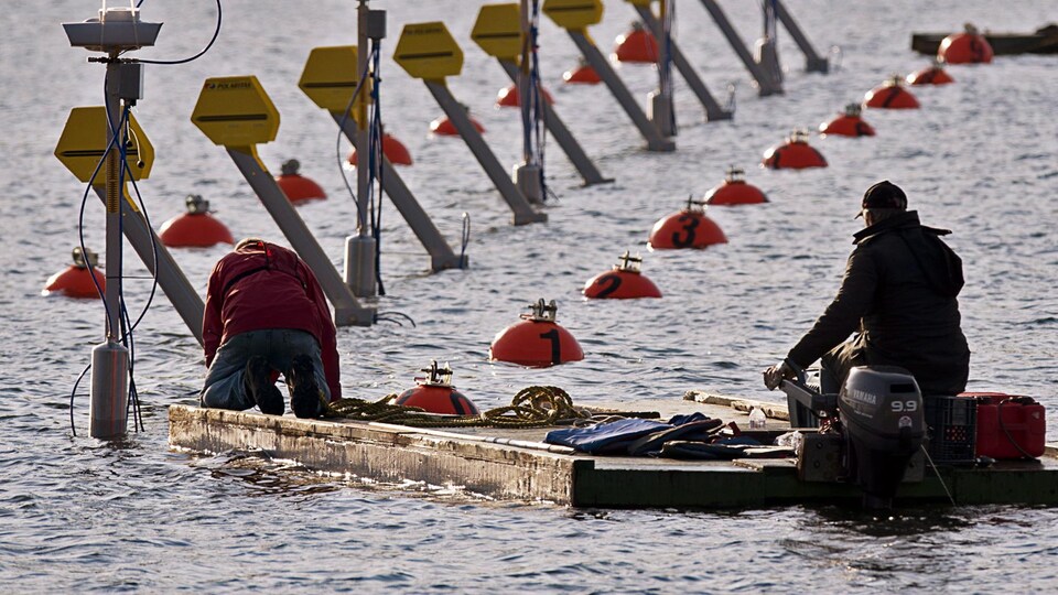 Deux hommes sont sur une embarcation sur un lac et vérifient le système de départ de course.