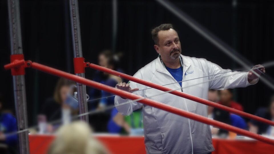 Un entraîneur surveille une athlète lors d'une compétition de gymnastique.
