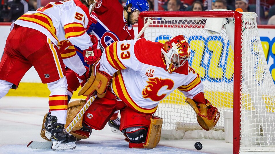 Le gardien des Flames David Rittich tente d'arrêter la rondelle avant qu'elle traverse la ligne rouge derrière lui. 