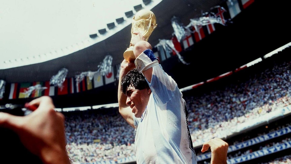 A player carried by his teammates lifts a trophy  