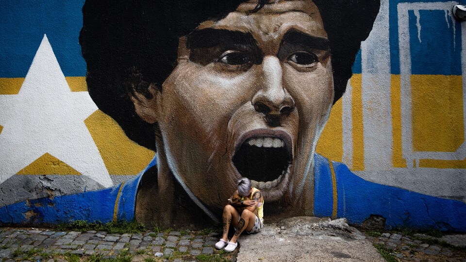 Une femme pleure devant une murale de Maradona.