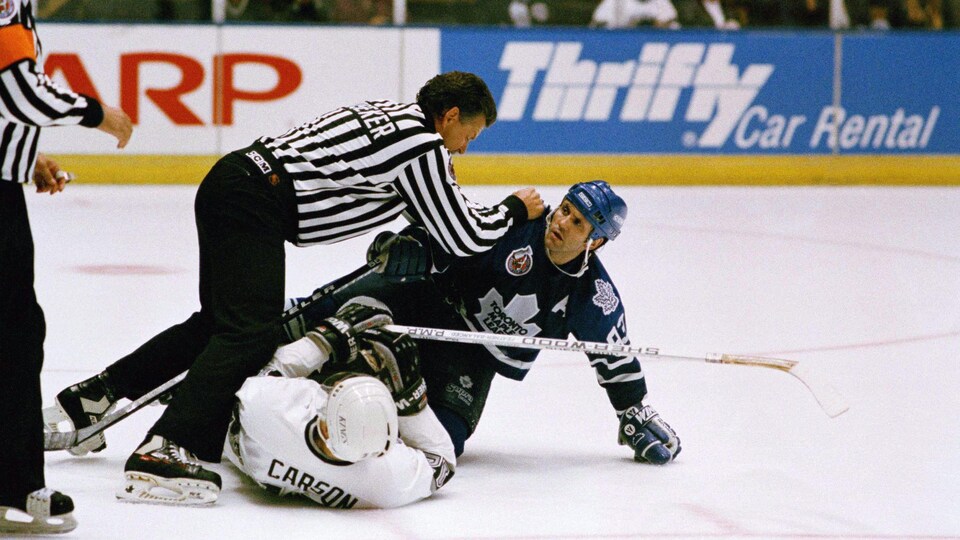 Deux joueurs sur la glace près d'un arbitre
