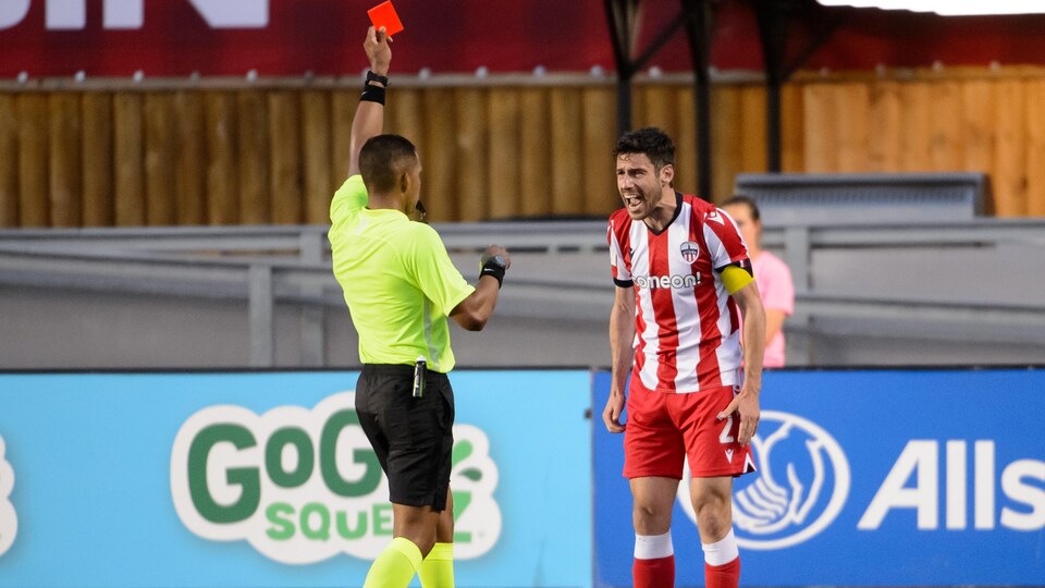 Un arbitre de soccer donne un carton rouge à un joueur pendant un match. 