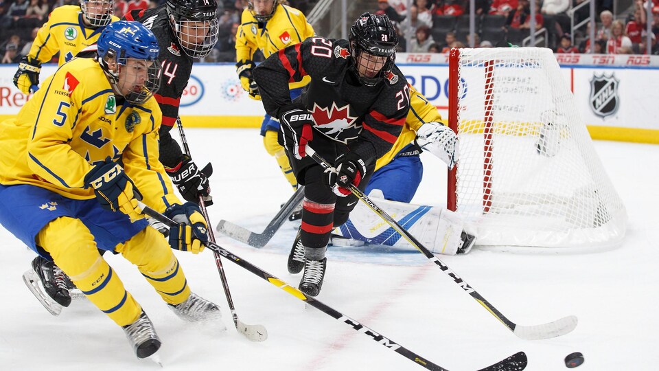Dylan Holloway tente de s'emparer de la rondelle lors d'un match du Canada face à la Suède, lors du Championnat Hlinka-Gretzky en 2018.