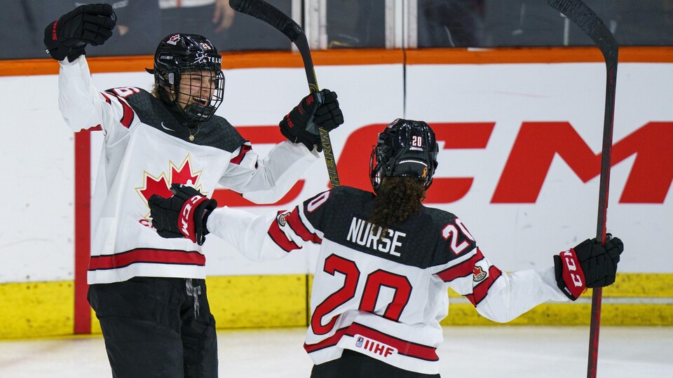 Deux joueuses du Canada s'apprêtent à s'enlacer pour célébrer un but.