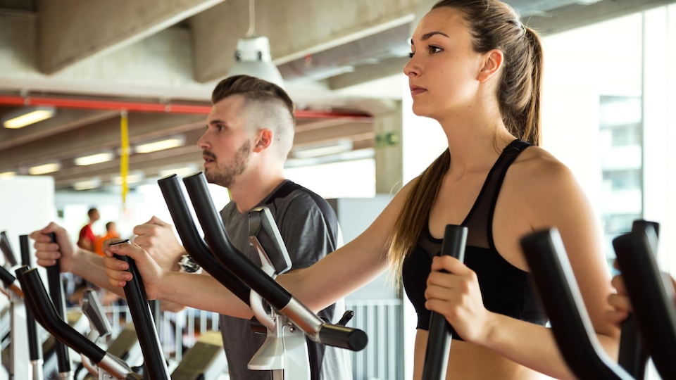 Un homme et une femme s'entraînent dans une salle de conditionnement physique.