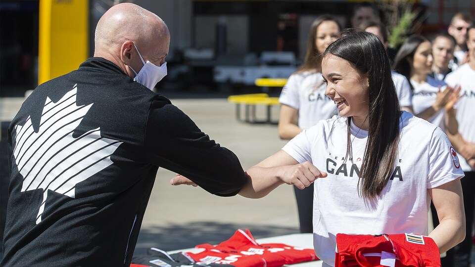 Éric Myles et Brooklyn Moors se cognent le coude après qu'elle eut reçu un manteau de l'équipe olympique du Canada.