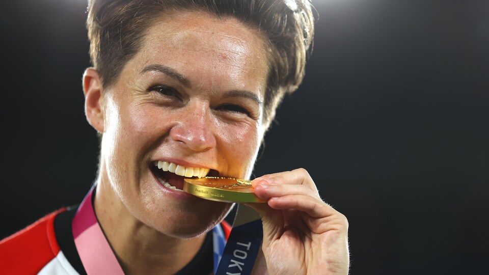 Une femme croque une médaille d'or.