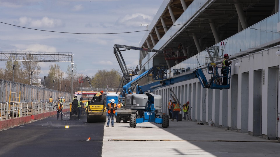 Overview of the Gilles-Villeneuve circuit pit alley, with utility vehicles, cranes and workers