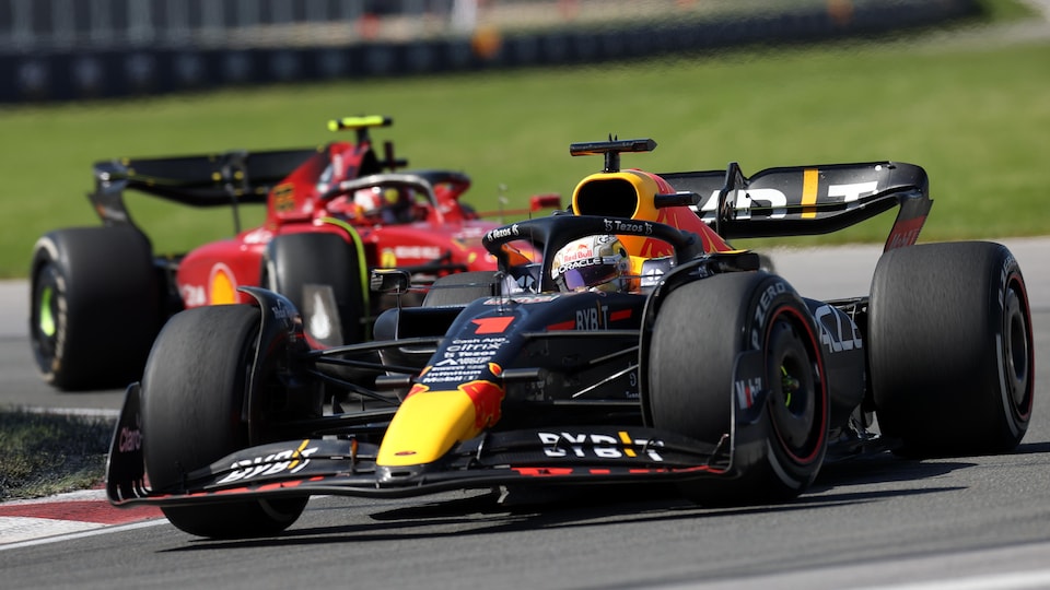 Due panchine monoposto di F1 si susseguono in una svolta a destra.
