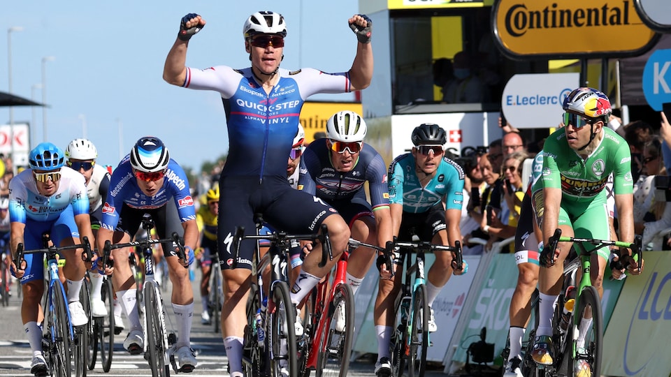 Le cycliste néerlandais lève les bras tout juste après avoir croisé l'arrivée de l'étape, devant un peloton de concurrents.