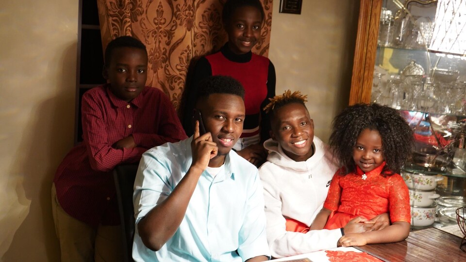 La famille sourit devant la caméra. Un d'entre-eux est au téléphone.          