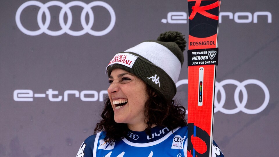Ses skis en main, elle sourit sur le podium. 