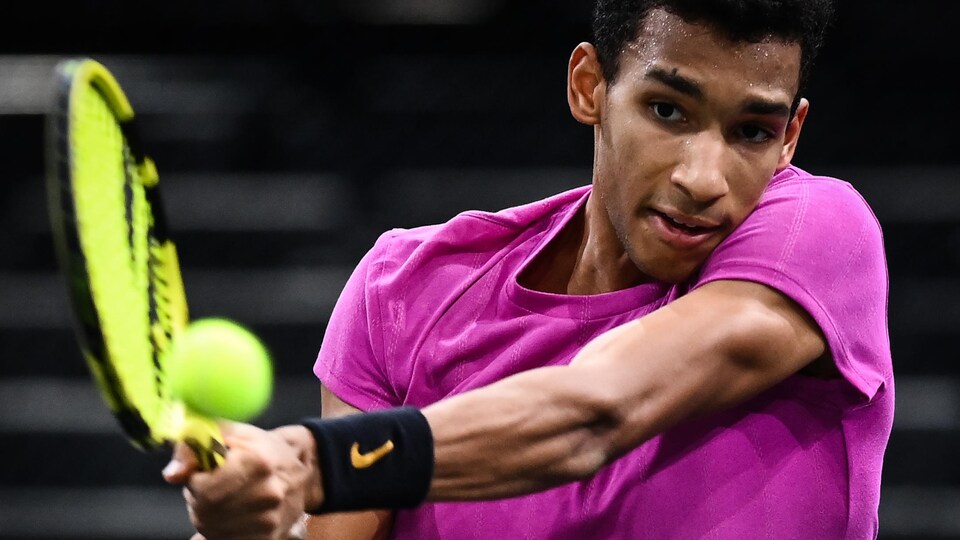 Il frappe une balle de tennis avec sa raquette.