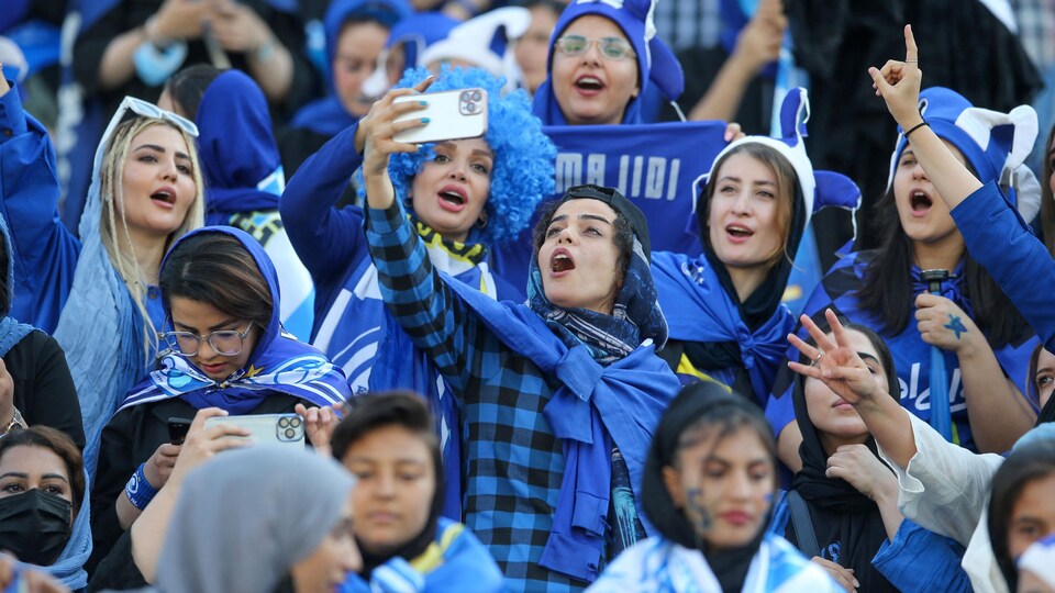 Des femmes se prennent en photo lors d'un match de soccer. 
