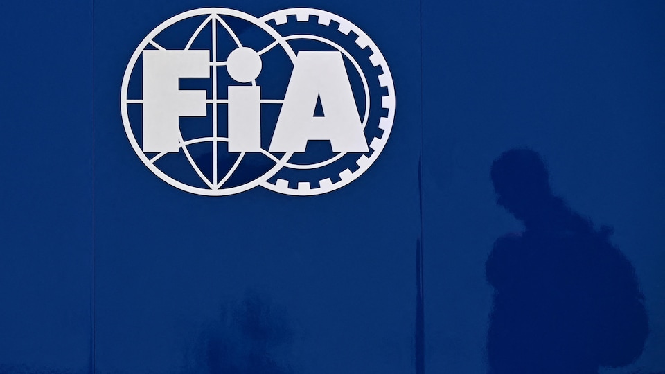 On voit la silhouette d'une personne qui marche le long d'un mur orné du sigle de la FIA.