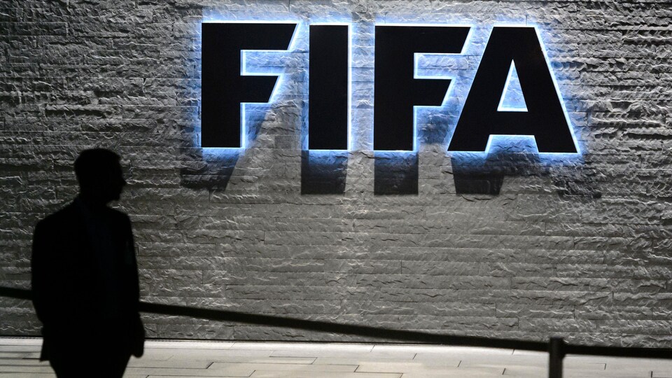 Une silhouette devant le logo de la FIFA.