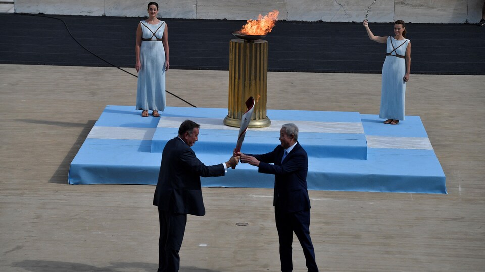 Le vice-président du comité d'organisation des Jeux de Pékin, Yu Zaiqing, reçoit la vasque olympique des mains du président du comité olympique hellénique, Spyros Kapralos.