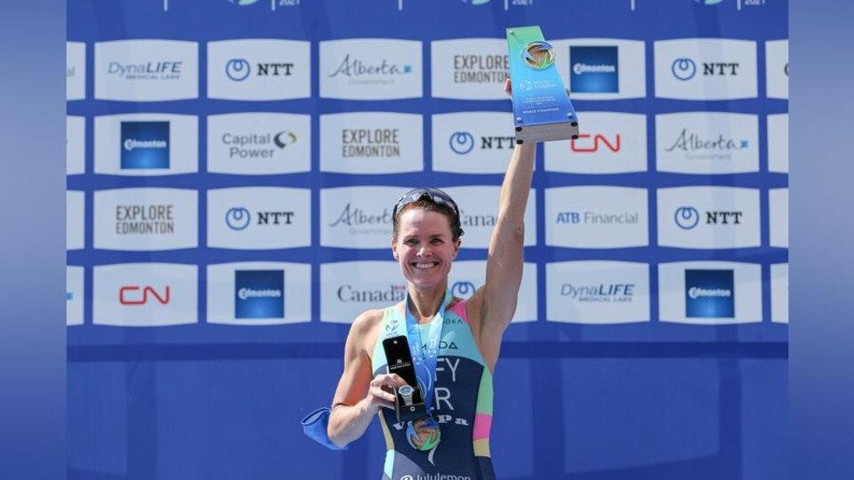 Elle tient son trophée dans sa main gauche levée.