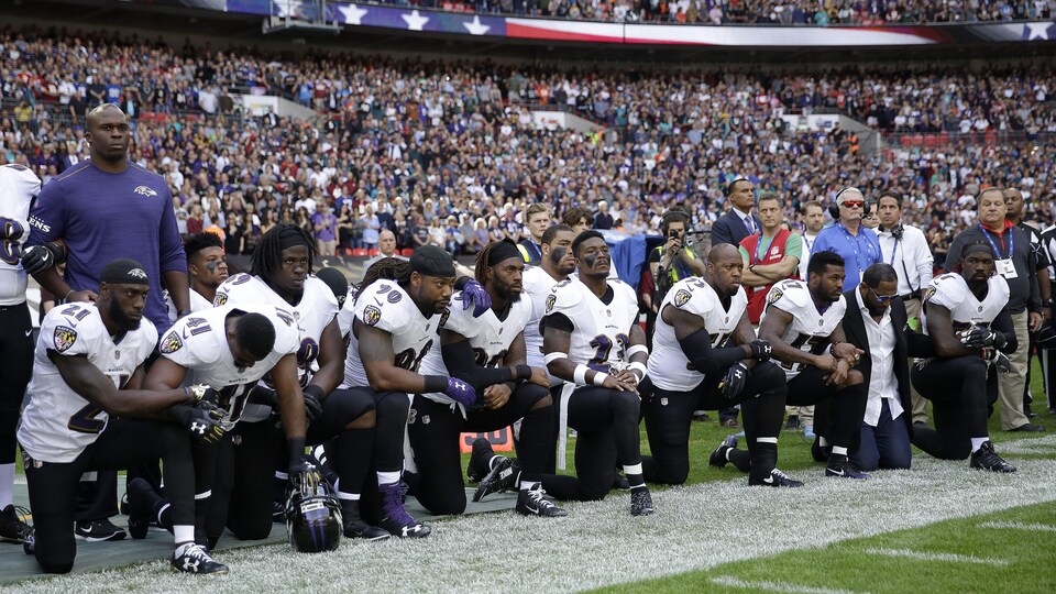 Des joueurs des Ravens de Baltimore et leur ancien coéquipier Ray Lewis (deuxième à partir de la droite) s'agenouillent au cours de l'interprétation de l'hymne national américain.