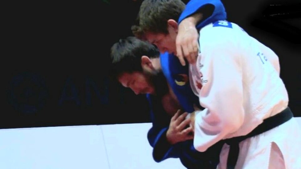 Un judoka soutient son adversaire blessé pour l'aider à marcher. 