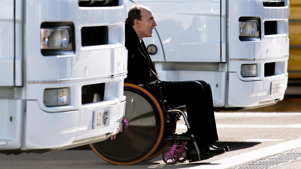 Un homme en fauteuil roulant près d'un autobus blanc.