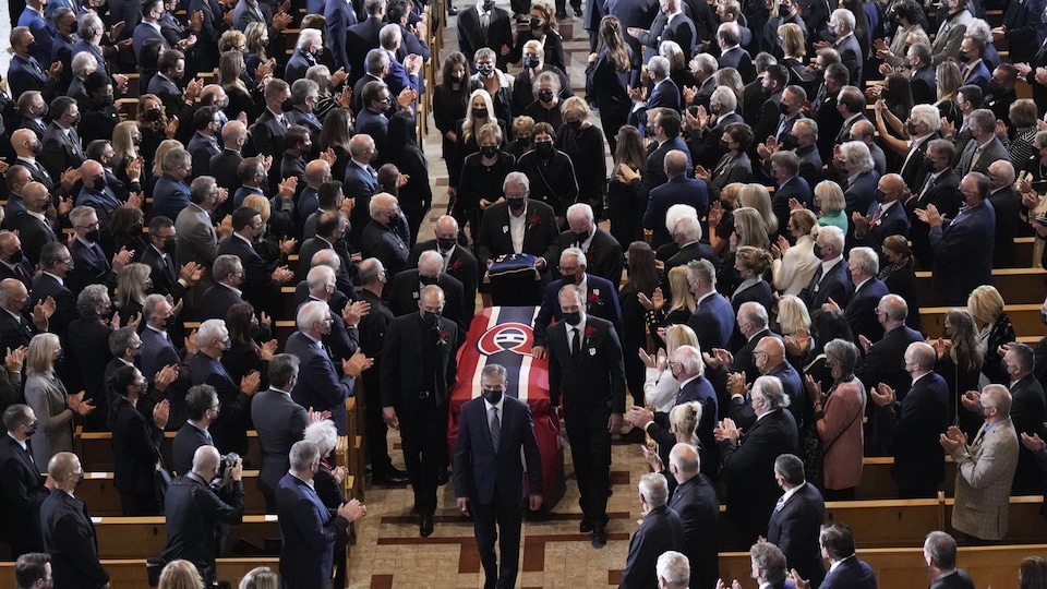 People in a cathedral applauded the passage of a coffin covered with a sheet in the colors of the Montreal Canadiens.
