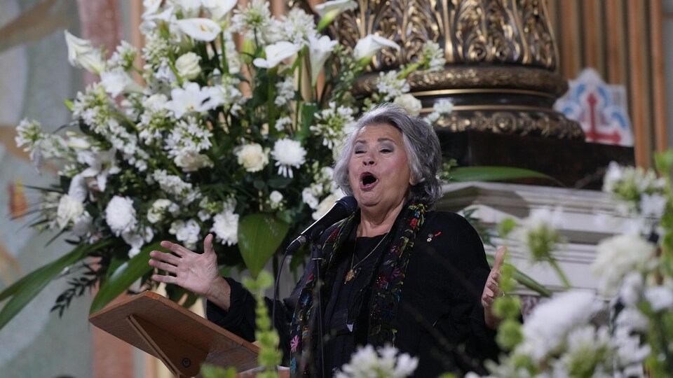 A woman sings at a funeral.