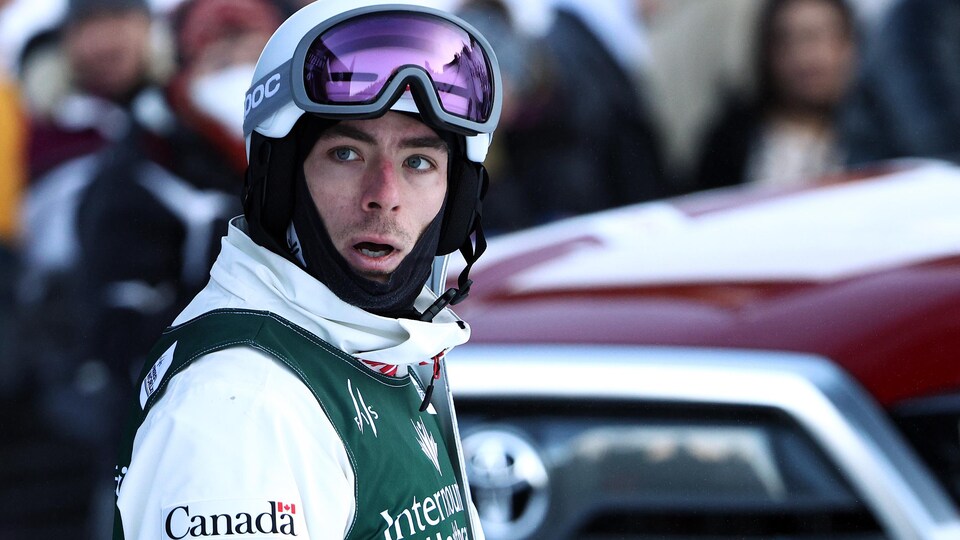Un skieur casqué tourne la tête sur sa droite pour apercevoir les résultats de la compétition. 
