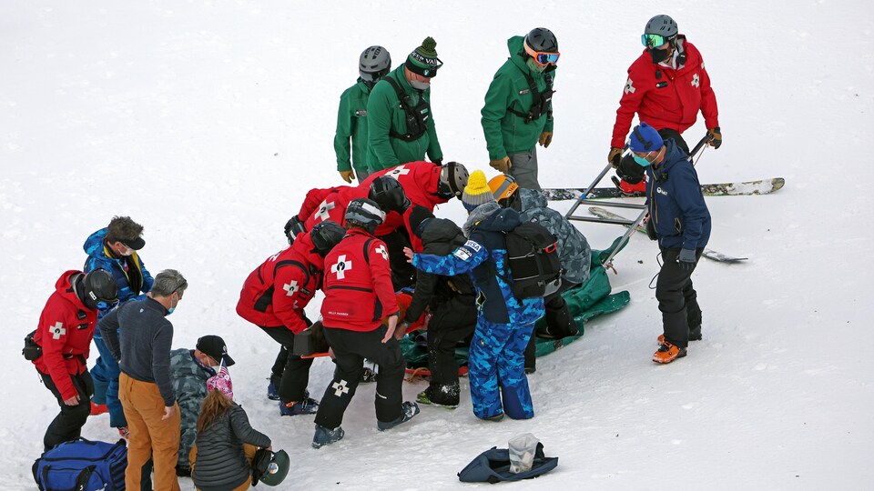 Des secouristes entourent un skieur blessé. 