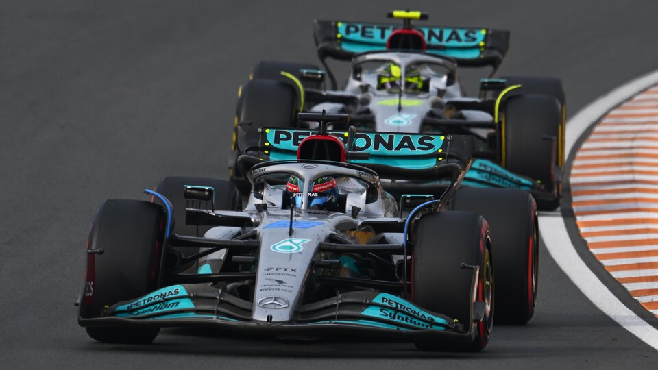 Deux monoplaces (de face) de la même équipe de F1 se suivent en piste.