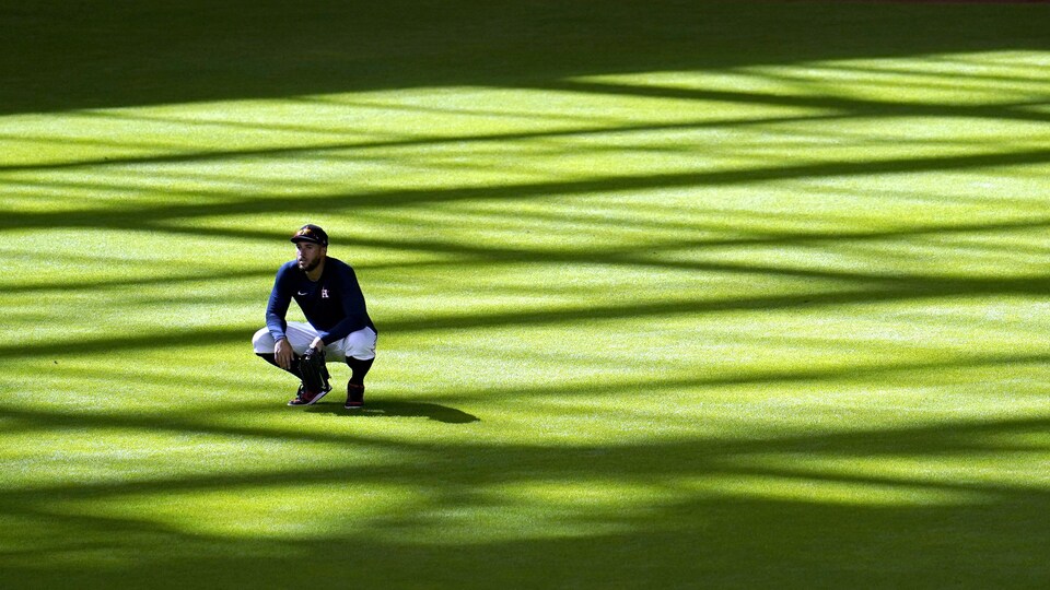 George Springer se trouve dans le champ centre d'un terrain de baseball. Il est accroupi.