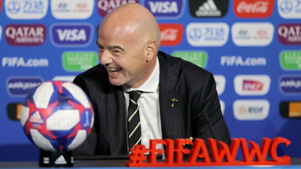 Il rit. Devant lui, un ballon et le mot-clic de la Coupe du monde féminine.