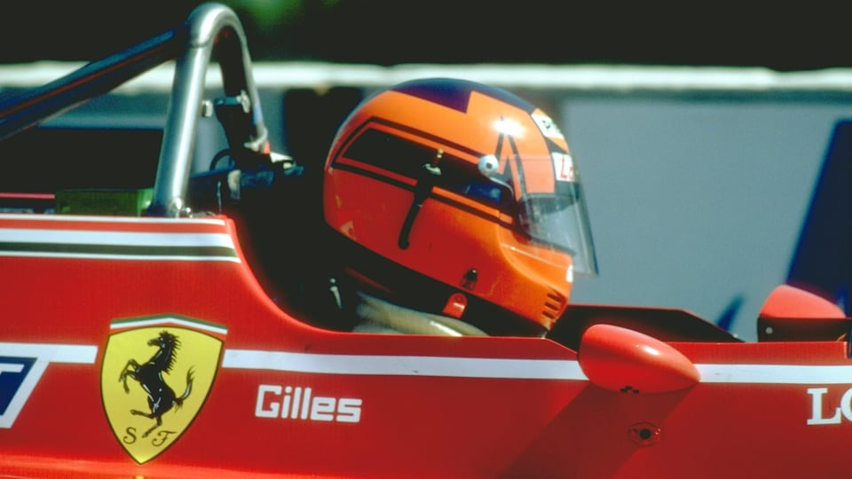 Un pilote de profil casqué dans sa voiture, le logo de Ferrari et l'inscription Gilles sont visibles sur la voiture. 